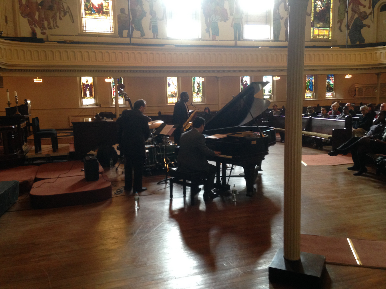 Inside church sanctuary with jazz combo performing in late-afternoon sunlight streaming through the windows.