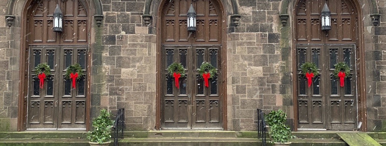 Front doors of church building with Christmas wreaths, falling snowflakes