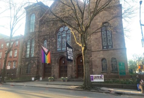 Photo of church facade with large banners flying, one for Black Lives Matter and the other Pride flag