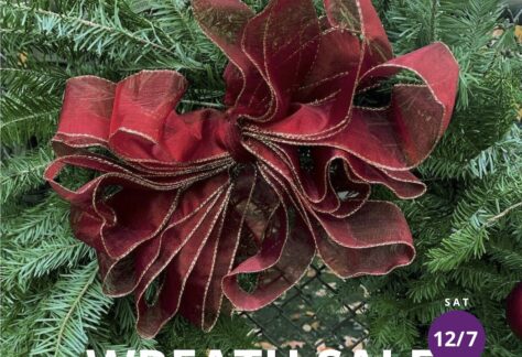 A Christmas Wreath of evergreen branches and fancy red ribbon with text "Wreath Sale"