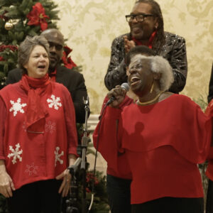 Church choir members in red sweaters performing, focus on soloist Janis Russell