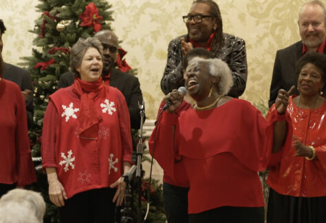 Church choir members in red sweaters performing, focus on soloist Janis Russell