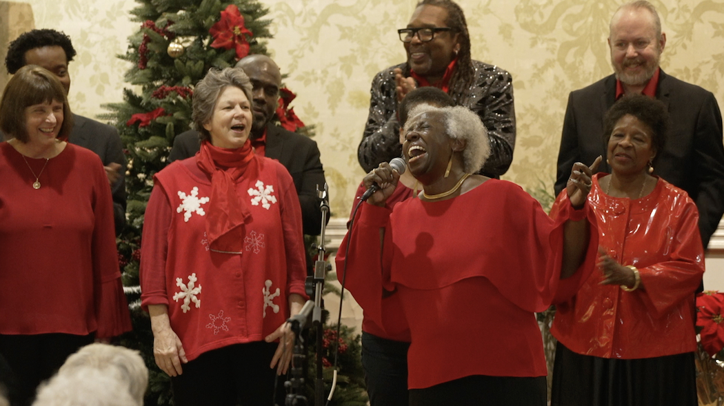 Church choir members in red sweaters performing, focus on soloist Janis Russell